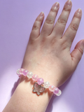A pink purple and white beaded bracelet with a sparkly butterfly charm 