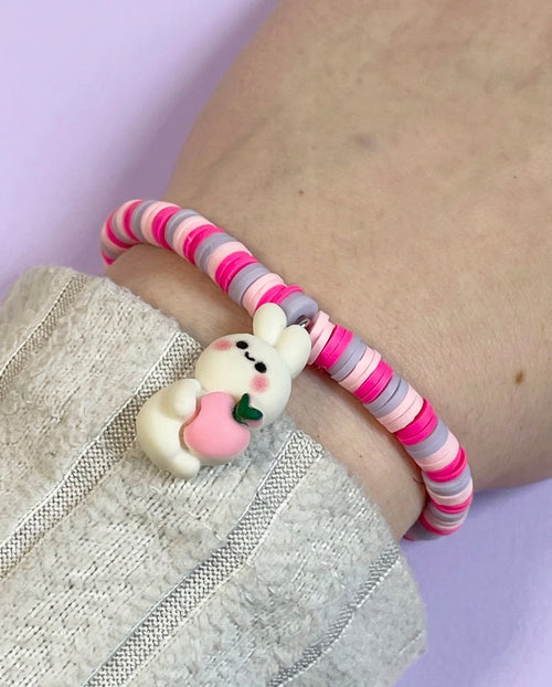 A beaded pink and purple bracelet with a white bunny charm 