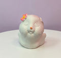 White ceramic bunny figurine with a pink flower behind its ear with a sleepy expression 
